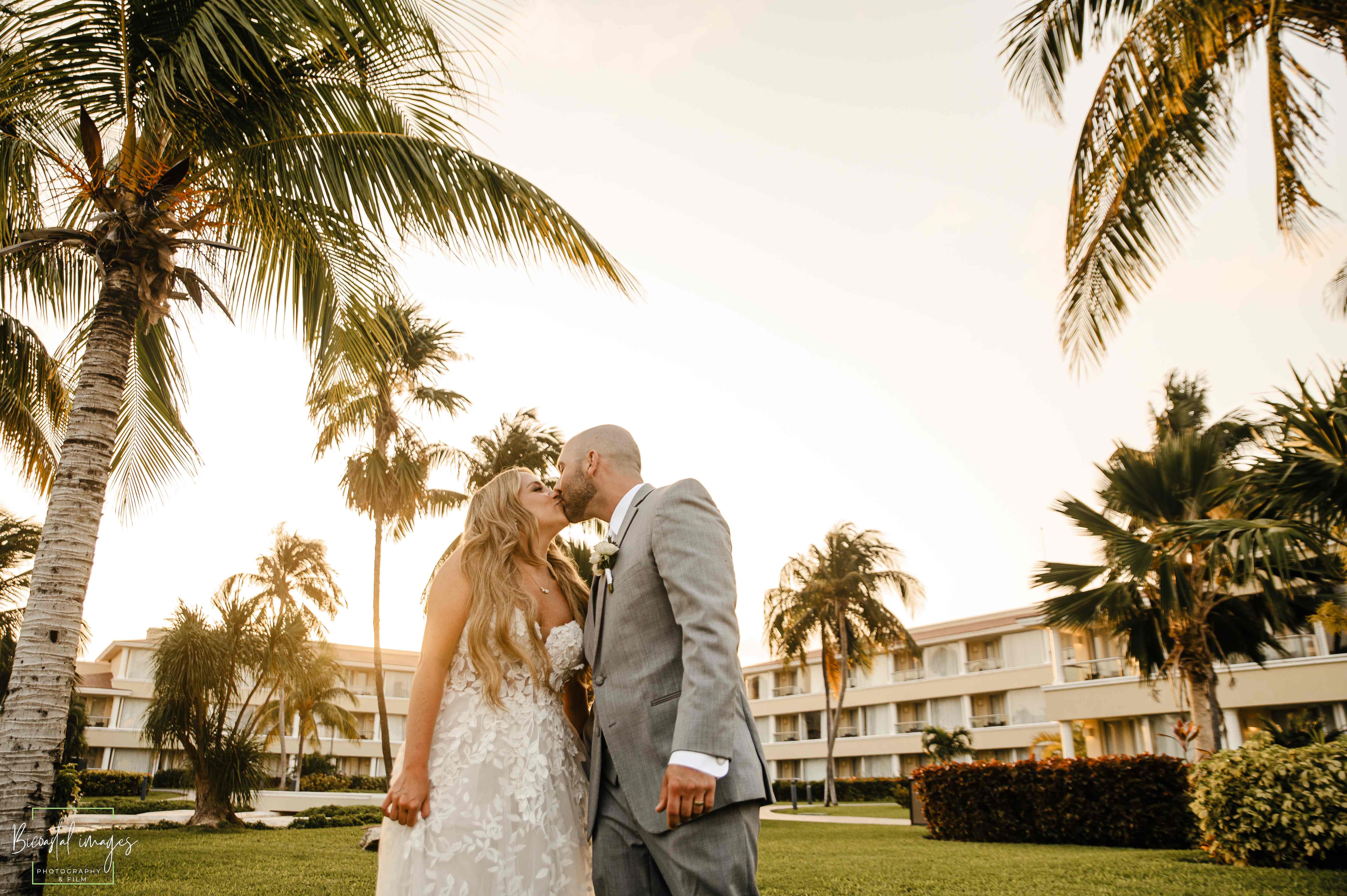 Golden hour couple kiss with palm trees and resort backdrop